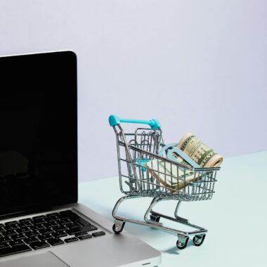 Shopping Cart with Money on Top of a Laptop